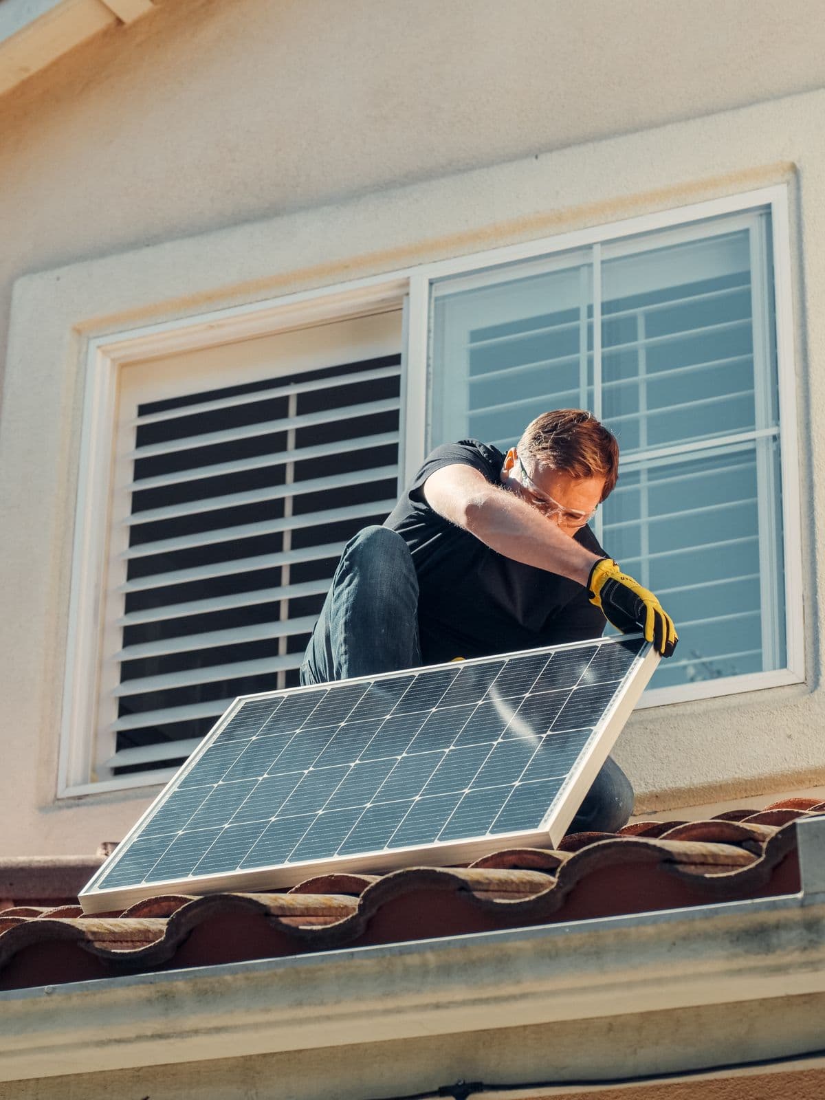 Technician installing a solar panel on a rooftop